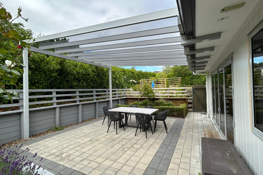 Residential ClearSpan pergola with a clear roof over a paved courtyard dining area